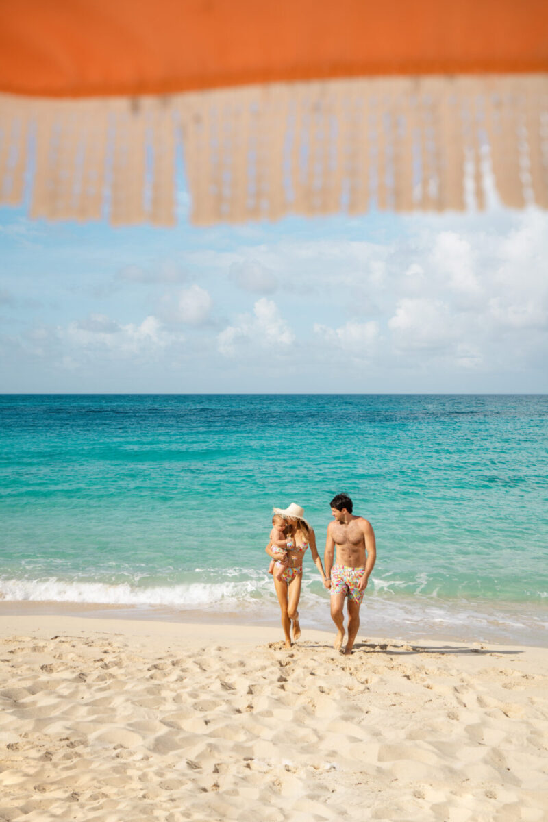 A picture of a family on a beach featured for a travel content about traveling with a toddler.