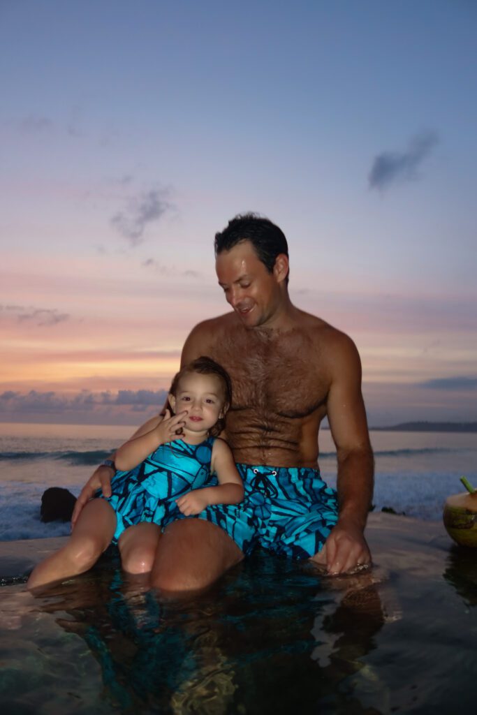 Father and toddler daughter in the pool at sunset at NIHI Sumba