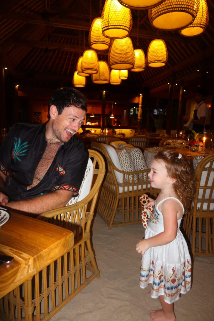 Father and daughter at dinner under woven lanterns at NIHI Sumba