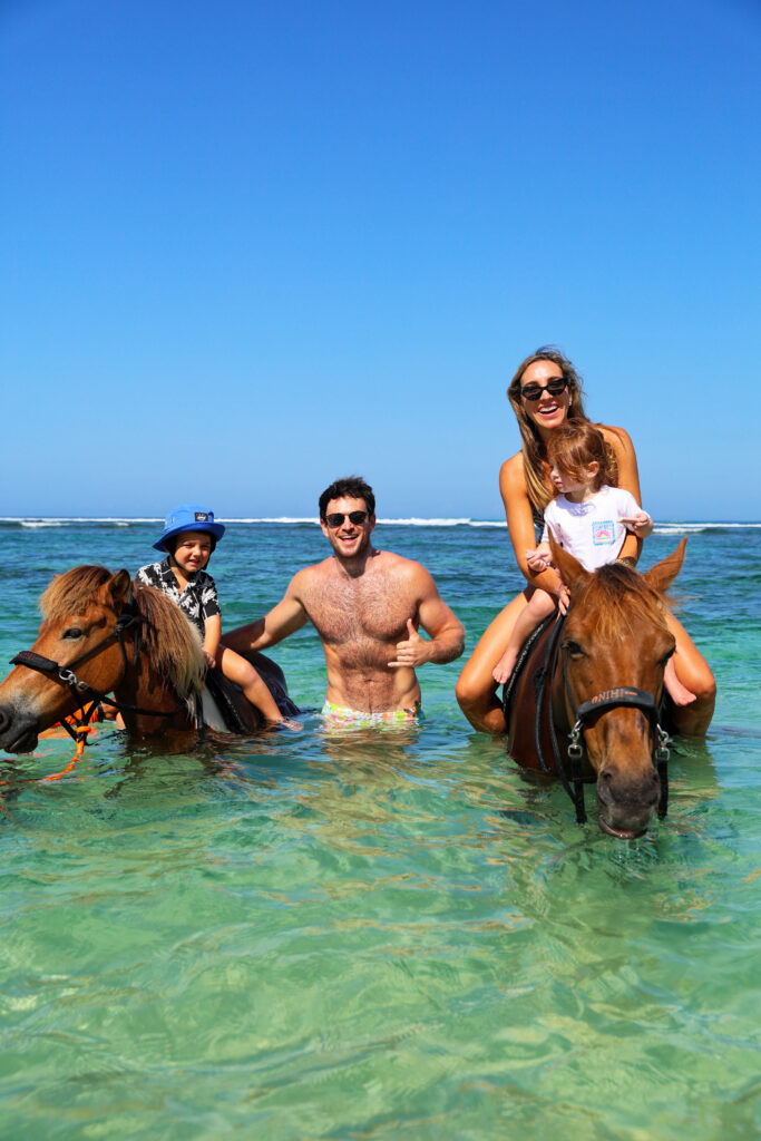 Family horseback riding in the ocean at NIHI Sumba