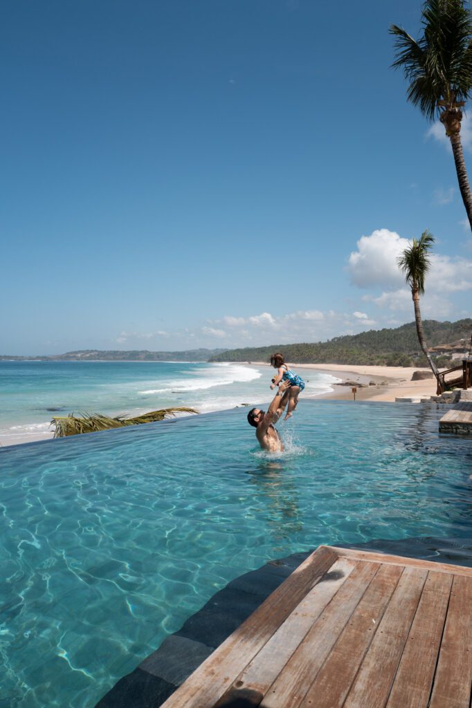 Family playing in the infinity pool overlooking the beach at NIHI Sumba