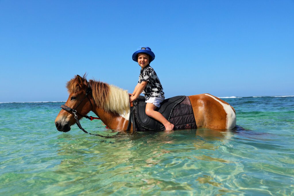 Jetset Christina's son riding a horse in the ocean at NIHI Sumba